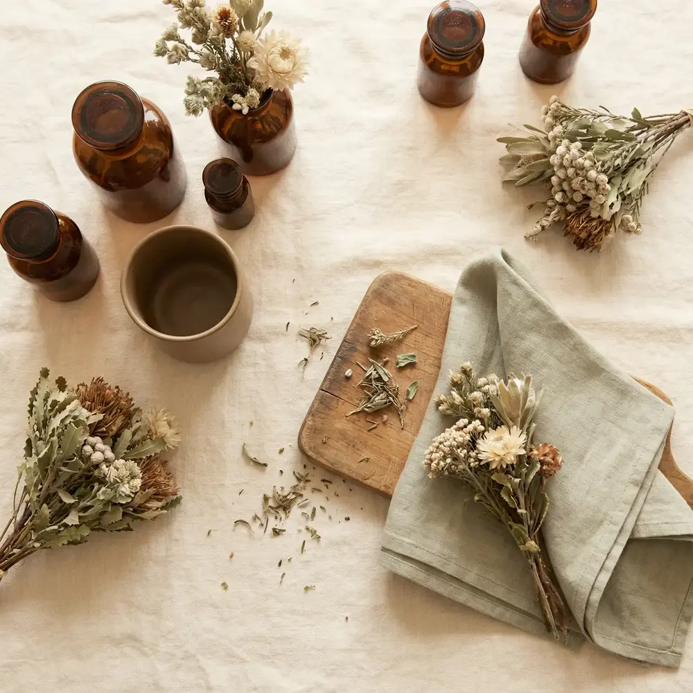 Dried herbs, flowers and amber apothecary bottles on linen